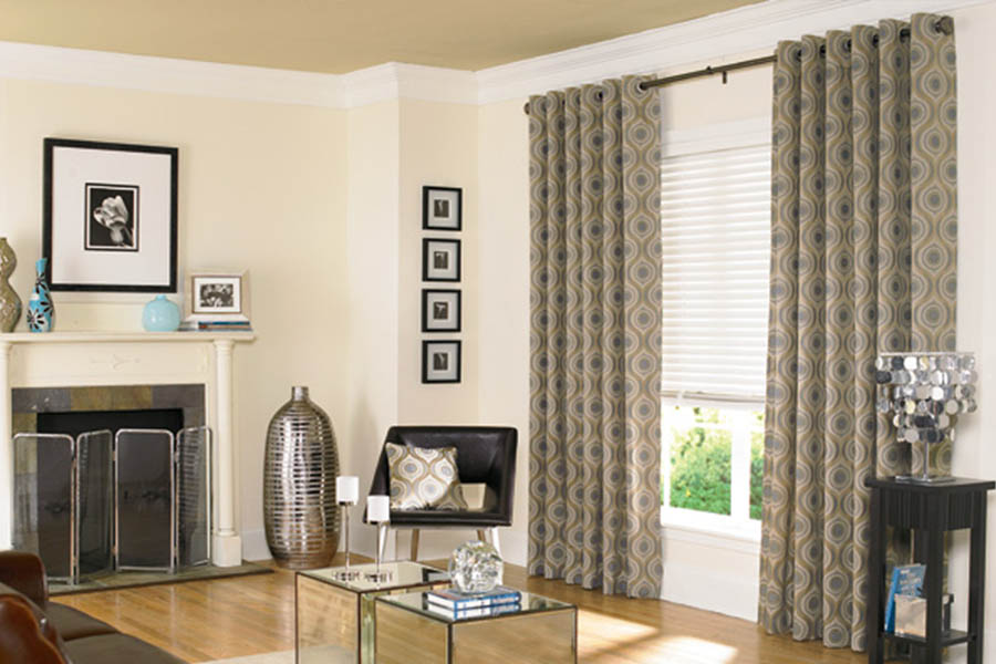 Sage green patterned curtains on white blinds in a living room
