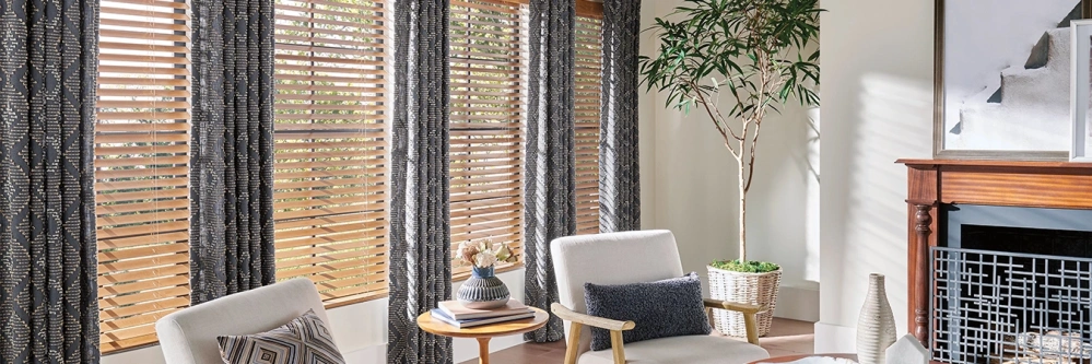 Patterned brown drapes with gray woven shades on large living room windows