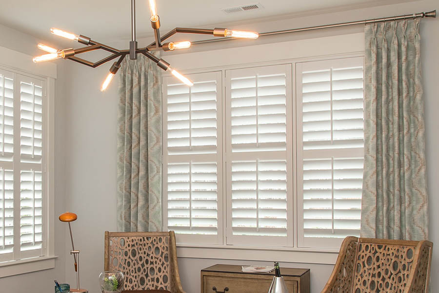 sage green and brown wavy pattern curtains with white polywood shutters in an office