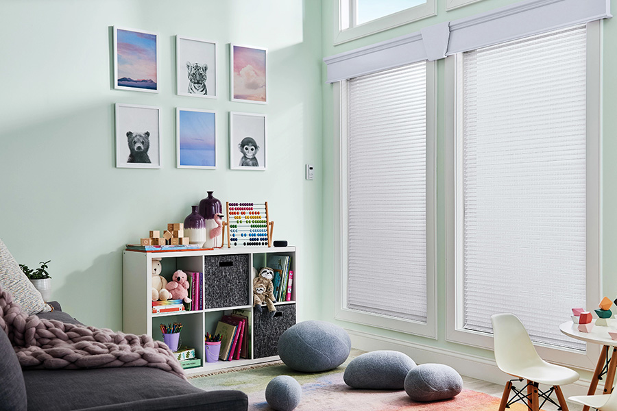 Cordless cellular shades are safe for a children's playroom but still beautiful. Sheer white shades inside a large playroom