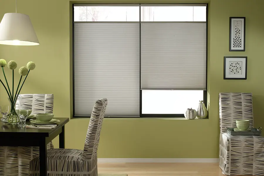 You can lower the top and raise the bottom of top-down/bottom-up shades at the same time. Gray cellular shades raised and lowered on a dining room window