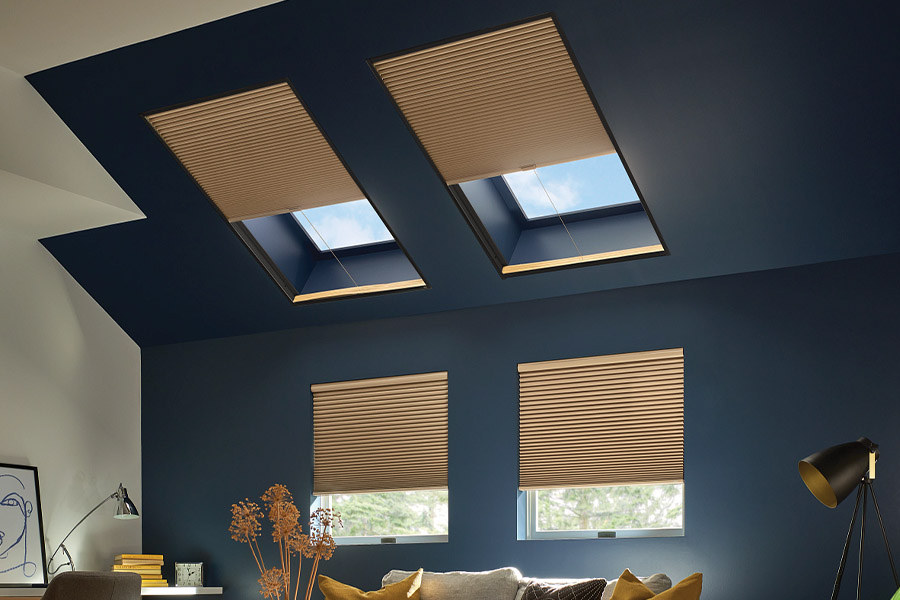 Can't reach a window? Put easy-to-use motorized window shades on high windows. Tan cellular shades on windows and skylights in a blue living room