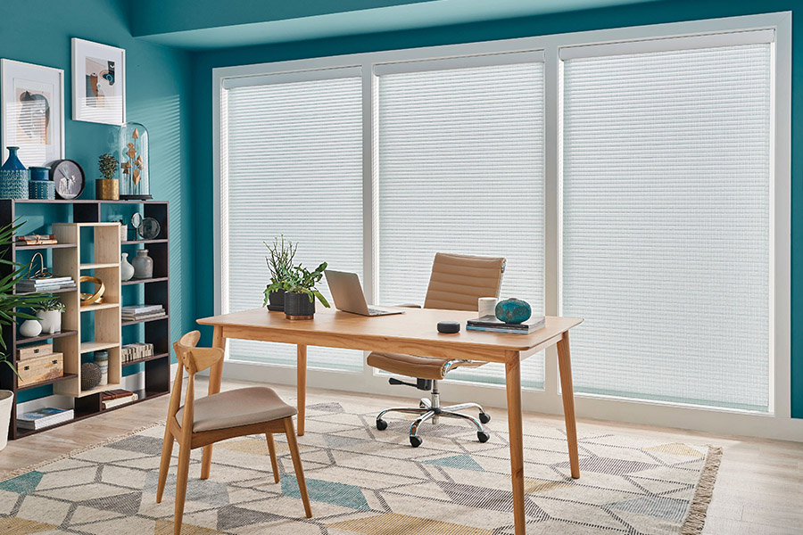 White cellular shades let you block noise and distractions outside so you can concentrate in your home office. sheer shades in a teal color office setting