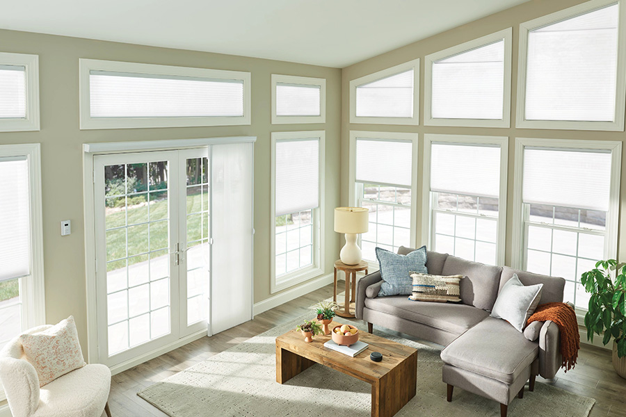 Crisp white cellular shades add brightness to the sunroom while ensuring extra privacy. sheer shades in a large sun room