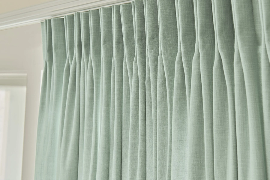 Thick blackout drapery blocks light while lending a sophisticated look to your window and home. Close-up view of green blackout drapes