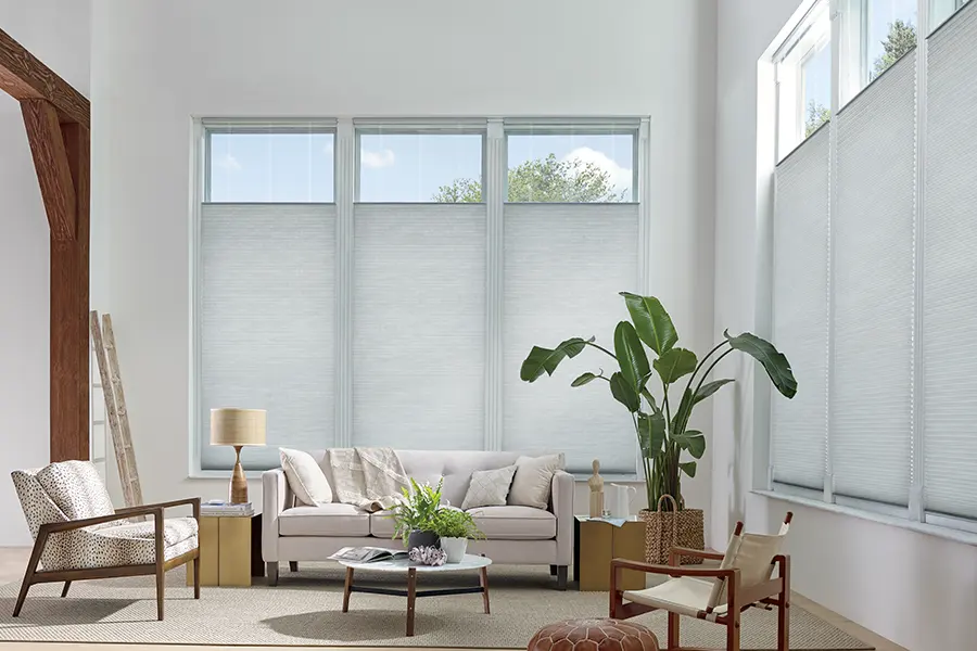 Top-down/bottom-up shades let you choose how to balance natural light and privacy. White sheer shades partially lowered at the top on tall living room windows