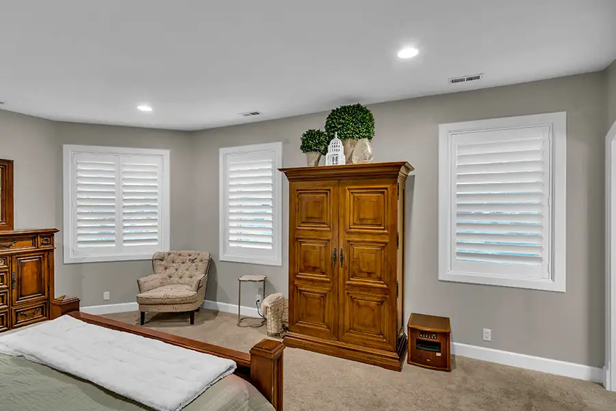 Polywood shutters are so easy to clean, you can even put them in kitchens and eating areas. White Polywood shutters on two large windows inside a large bedroom