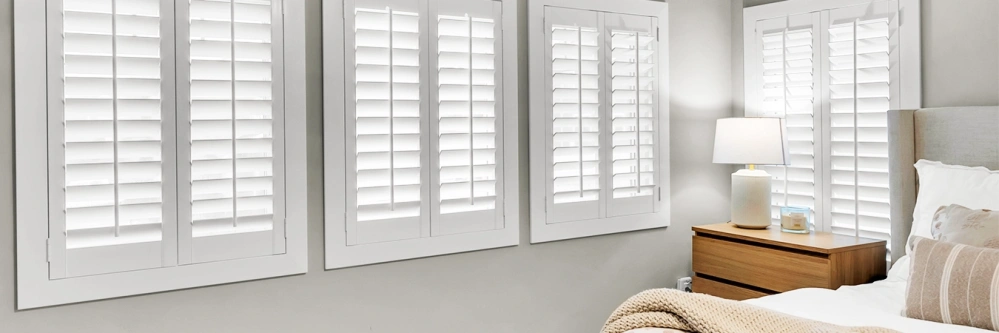 White Polywood shutters on windows in a white bedroom