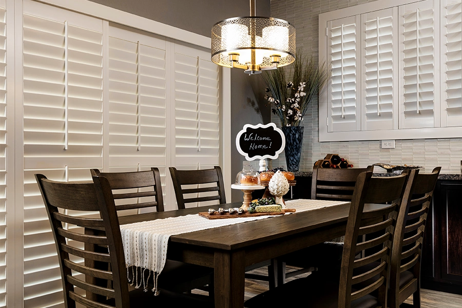 Polywood shutters are the top choice for patio door window treatments. White Polywood shutters closed on a patio door in a dining room