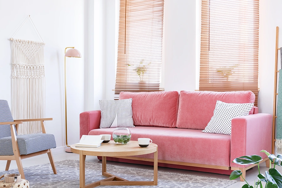 From classic wood blinds to long, flowing fabric drapes, you'll find many different kinds of window treatments out there to consider for your home. Wood blinds on two windows in a trendy living room