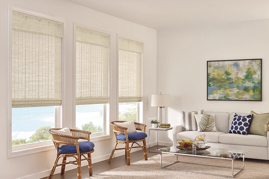 Woven shades let some light in when you want to brighten up a north-facing room. Beige motorized woven shades on tall living room windows