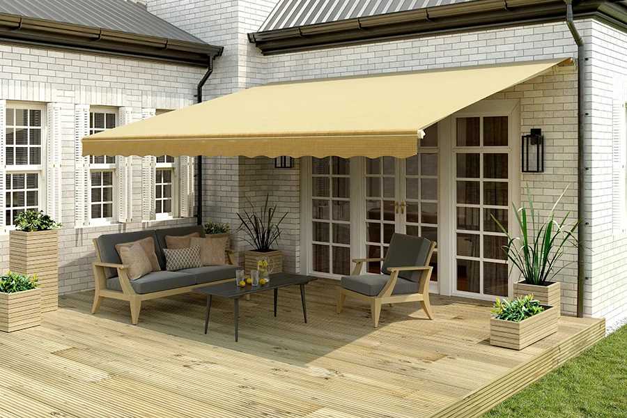 Protect your outdoor space from the sun and rain with a beautiful, durable retractable awning from Sunburst! A beige retractable awning over a wood deck on the back of a white brick house